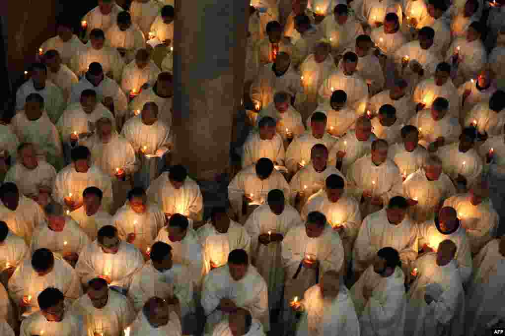 Roman Catholic clergymen hold candles as they circle the Anointing Stone during the Holy Thursday Mass at the Church of the Holy Sepulchre in Jerusalem's old city. (AFP/Gali Tibbon)