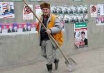 A municipal worker passes a wall covered with election posters in Grozny before the poll (AFP)