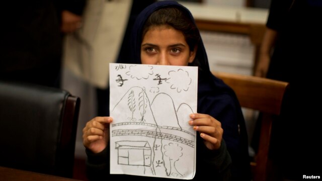 At a news conference in Washington on October 29, Nabila Rehman holds up a picture she drew depicting the U.S. drone strike on her Pakistani village which killed her grandmother.