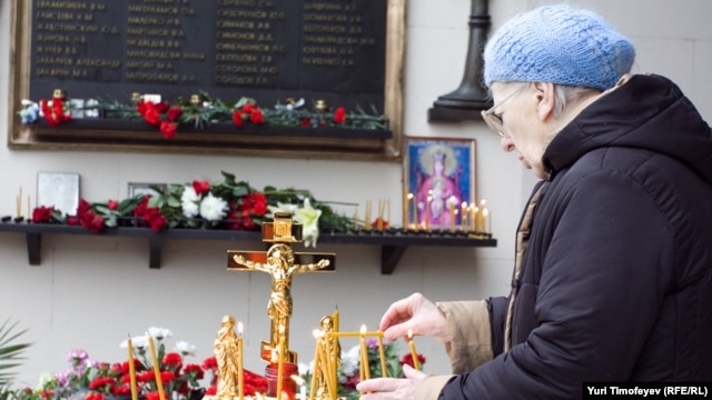 The victims' relatives displayed photographs of those killed, laid flowers, and lit candles near the entrance to the theater. 