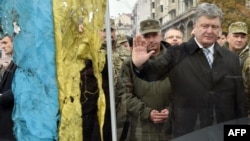 Ukrainian President Petro Poroshenko pays his respect to a Ukrainian flag found close to the remains of fallen soldiers in eastern Ukraine. Local elections this week are being seen as an important barometer of how Ukrainians think his administration is handling the country's myriad problems.