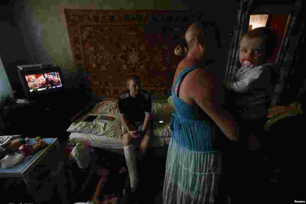 Anya Savchenko (right), Sergei Smirnov, and their 9-month-old baby, who have fled fighting in Slovyansk, stand in their temporary accomodation in the town of Nyzhnya Krynka.