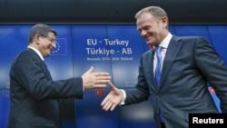 Turkish Prime Minister Ahmet Davutoglu (left) shakes hands with European Council President Donald Tusk after meeting to discuss Europe's migrant crisis. Turkey's neighbors fear that, if Ankara toughens its visa regime to help stem the flow of migrants into Europe, it could also drastically reduce the number of countries whose citizens can currently enter Turkey easily.