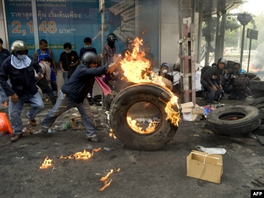 A demonstrator pushes a burning tire during clashes with security forces in Bangkok on May 15.