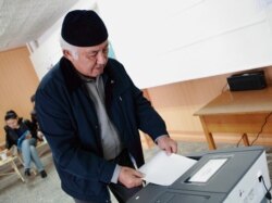 A voter in Bishkek casts his ballot into one of the new automatic ballot boxes.