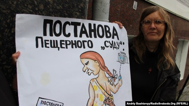 A Lutsenko supporter holds a placard that accuses the court of holding a staged production.