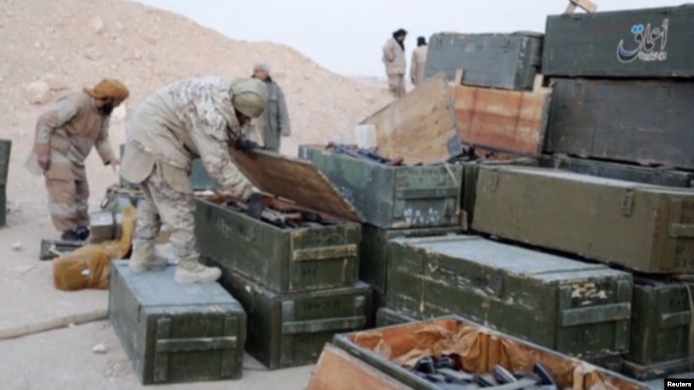 IS fighters search weapons boxes at a Russian base in what is said to be Palmyra, in this still image taken from video uploaded to social media on December 13.