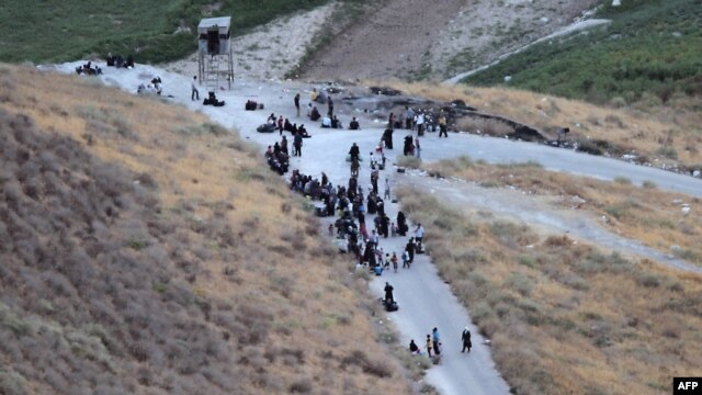 Newly arrived Syrian refugees sit on the road after crossing the border from Syria into Jordan, near the town of Ramtha, in early September.