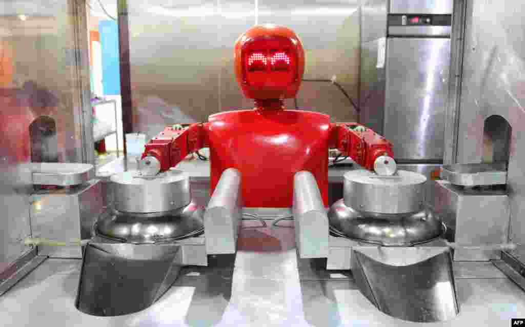 A robot cooks in a robot-themed restaurant in Harbin in northeast China's Heilongjiang Province. Twenty robots perform a variety of chores, from ushering in guests to waiting tables and cooking dishes. (AFP)