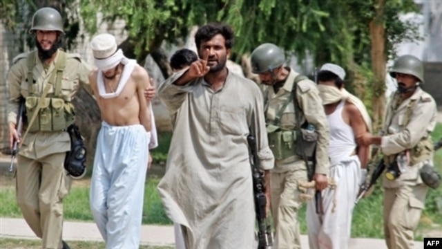 Pakistani Army soldiers escort blindfolded, detained militants who were holed up in the Red Mosque  in Islamabad on July 5, 2007.