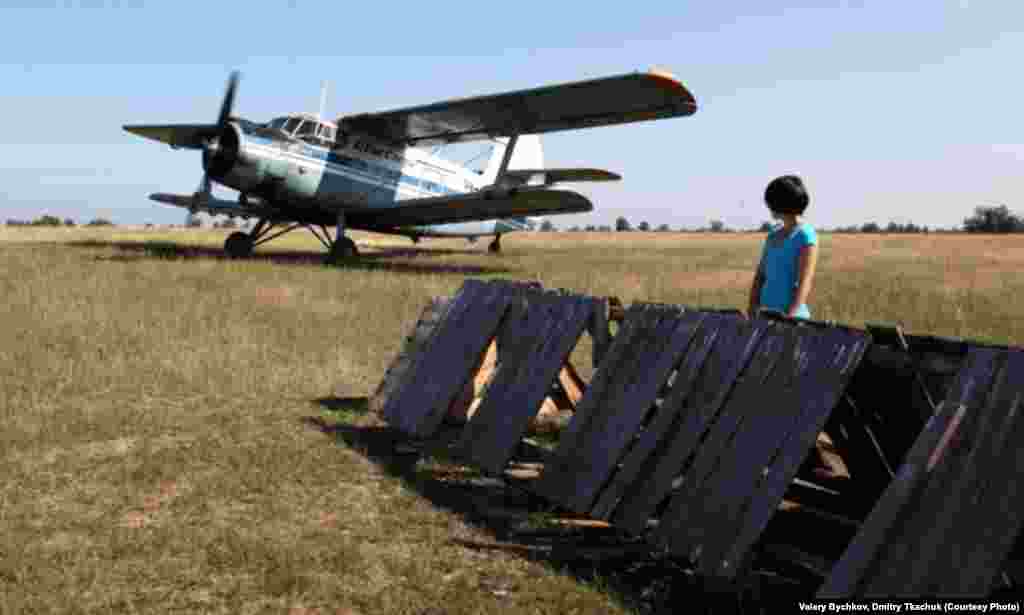 A woman watches as an airplane, a vital lifeline to the outside world, lifts off.