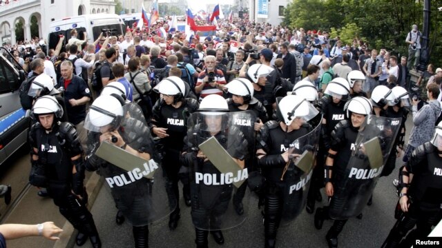 Russian soccer fans walk protected by Polish riot police in Warsaw.