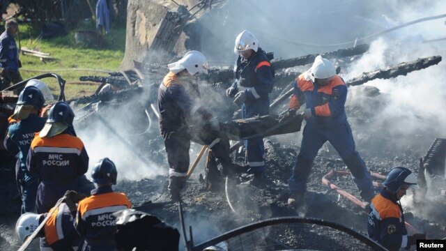 Russian emergency workers carry the burned body of a victim from the debris of a psychiatric hospital destroyed by fire.
