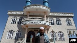 Men stand in front of a Shi'ite mosque in Kabul where intelligence forces killed what they say were two Pakistani terrorists in police uniforms.