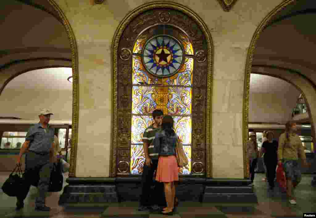 A couple kisses in front of a stained-glass panel at the Novoslobodskaya metro station, which was built in 1952.