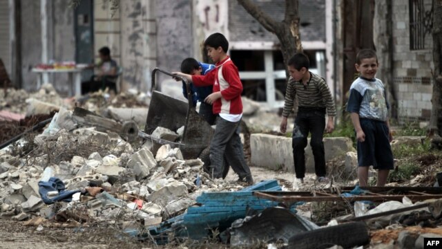 Children remove rubble from the entrance to their house in the Bab Amro neighborhood of Homs.