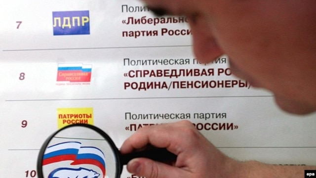 A man looks at the logo of the pro-presidential United Russia party showed among others on the election poster at a polling station in Kemerovo.