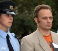 A Georgian police officer escorts one of the detained Russian 'spies' today (InterPressNews)