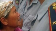 Қартаң әйел түрмедегі баласы азап көріп жатқанын айтып, абақты алдында полицейге жылап тұр. Алматы. 30 шілде 2010 жыл. (Көрнекі сурет)