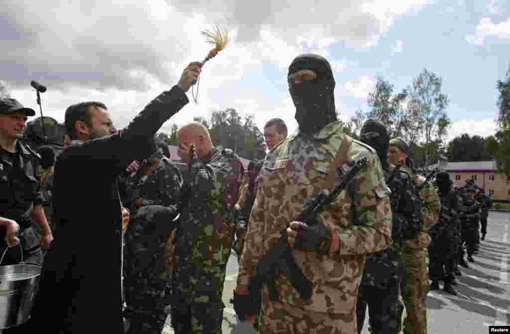 A clergyman sprinkles holy water on members of the "Donbass" self-defence battalion attending a ceremony to swear an oath of allegiance for a reserve unit of the National Guard of Ukraine, near Kyiv, June 23. (Reuters/Valentyn Ogirenko)