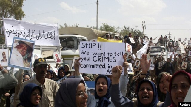 Residents of Camp Ashraf demonstrate in front of reporters touring in a bus on April 9, a day after their clashes with the Iraqi security forces.