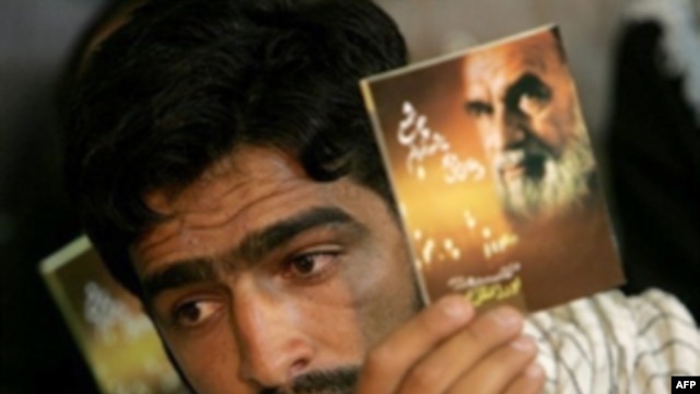A man in 2007 holds a portrait of Ayatollah Ruhollah Khomeini during a memorial ceremony to mark the 18th anniversary of Khomeini's death at his mausoleum in Tehran.
