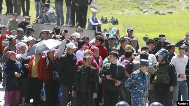 Riot police form a line near people who gathered at the settlement of Nizhnaya Alaarcha outside Bishkek on April 20.