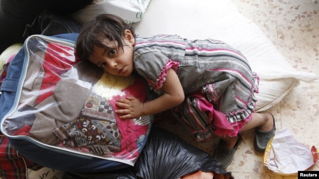 A Syrian girl lies on top of luggage at a makeshift refugee camp inside Iraq after crossing the Iraqi-Syrian border at Abu Kamal-Qaim, the main border post between the two countries, on July 24.