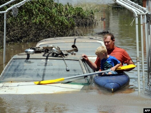 A man and his son kayak past flooded cars in Bundaberg, Australia, on December 31.