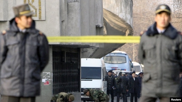Kyrgyz policemen stand guard as security personnel work on the site of a blast in Bishkek on November 30, 2010. Authorities blamed it on a previously unknown group.