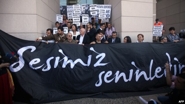 Supporters of world-renowned Turkish pianist Fazil Say stand behind a banner reading "Our voice is with you" during a protest held outside an Istanbul court, on October 18.