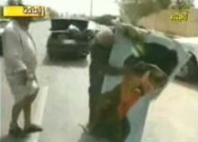 Iraq -- screen grab from Al-Arabiya of Abu Tahsin striking portrait of Saddam Hussein in Baghdad on 09apr2003