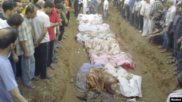 People gather during the mass burial of people whom activists say were killed by forces loyal to Syria's President Bashar al-Assad in Jdeidet Artouz, 01Aug2012