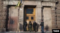 Ukrainian antigovernment protesters stand at the entrance of the Agricultural Ministry building in Kyiv which they occupied late last week.