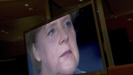 German Chancellor Angela Merkel is seen on a TV monitor as she prepares to record her annual New Year's speech at the Chancellery in Berlin.
