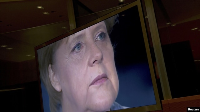 German Chancellor Angela Merkel is seen on a TV monitor as she prepares to record her annual New Year's speech at the Chancellery in Berlin.