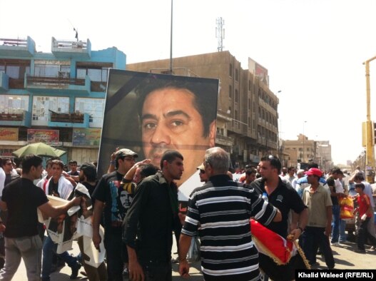 Protesters on Baghdad's Freedom Square rally against corruption and the poor state of public utilities while carrying photos of Iraqi civil activist Hadi al-Mehdi, who had co-organized a number of regular Friday antigovernment protests until he was murder