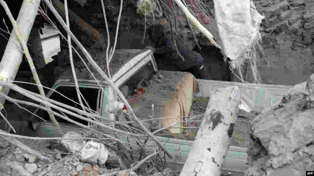 A man inspects a destroyed car trapped under the rubble of a house in the eastern Iranian village of Shaj after an earthquake struck the region. The quake, which registered 5.5 in magnitude, killed at least eight people. (AFP/Mojtaba Ghorgi)