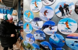 Сочи олимпиадасының белгілері салынған сувенирлік бұйымдар сатып тұрған адам. Адлер, 27 қаңтар 2014 жыл.