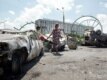 Residents walk past burned cars after the clashes in Andijon