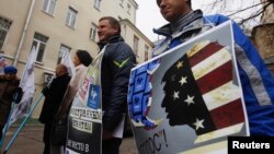 Protesters hold up signs outside the Moscow office of the election-monitoring NGO Golos accusing it of being a foreign agent in April 2013.