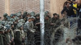 Egyptian soldiers prevent demonstrators from crossing over a barbed-wire fence as thousands gather near the presidential palace in Cairo to protest against a draft constitution and President Muhammad Morsi's sweeping decree.