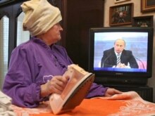 Russia -- A woman irons as she watches a TV broadcast of President Vladimir Putin's news conference, Stavropol, 14Feb2008