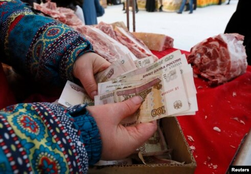 A meat vendor counts Russian ruble banknotes at an open-air food fair in Krasnoyarsk, Siberia.