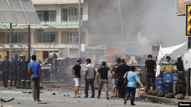 Residents gather at the site of a bomb attack in central Baghdad on July 31 that killed 20 people.