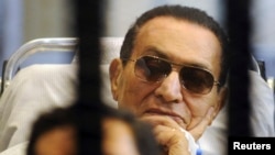Former Egyptian President Hosni Mubarak sits inside a cage in a courtroom at the police academy in Cairo on April 13.