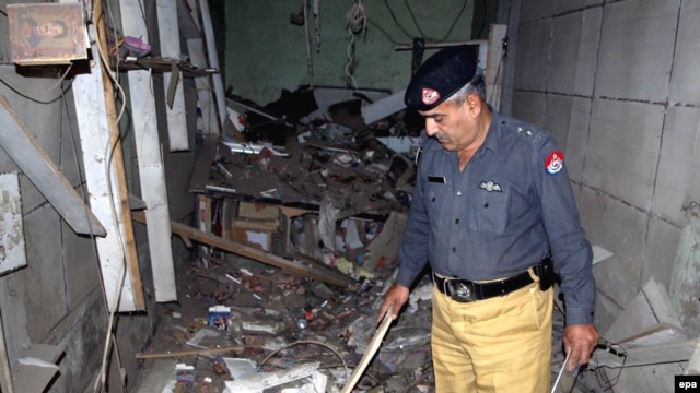 A police official inspects a damaged music shop after a bomb explosion in Charsadda, a town in the Northwest Frontier Province, in 2009.