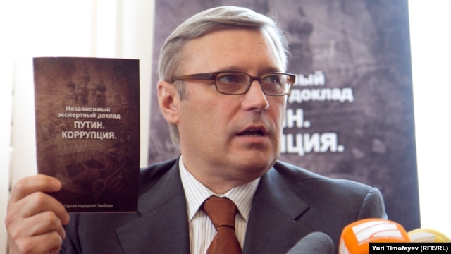 Former Prime Minister Mikhail Kasyanov holds up a copy of the report "Putin. Corruption," at its presentation on March 28.