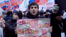 A government supporter holds a sign saying, "Russian Journalist: Don't Be A Prostitute!!!" at a pro-Kremlin rally in Moscow on December 12.