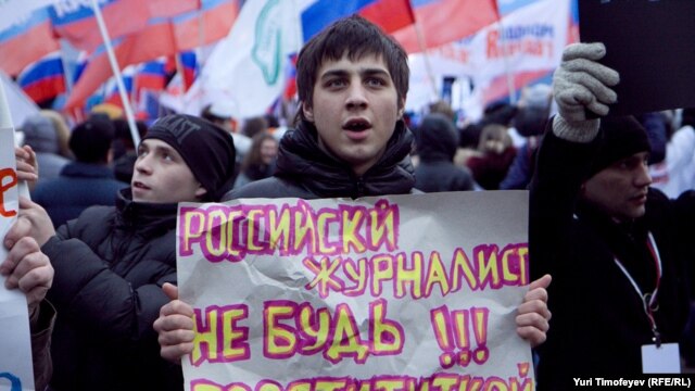 A government supporter holds a sign saying, "Russian Journalist: Don't Be A Prostitute!!!" at a pro-Kremlin rally in Moscow on December 12.